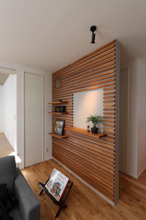 角材のルーバーで飾り棚を可動できるデザイン壁