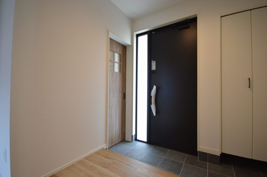 【玄関】</br> 土間収納への入口、旦那さんの趣味室への入口もある、間口の広い玄関。</br> 片袖FIXの玄関ドアで採光を確保。