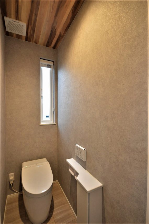 ベースはグレーの壁紙で、天井だけ個性的な木目に。トレンドのおしゃれなトイレ。</br> 洗面スペースの近くなので、タンクレストイレにしても室内に手洗い要らず。</br>