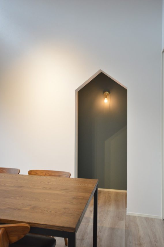 居室への入口はアクセントクロスと真鍮製のライトでインテリアのように。