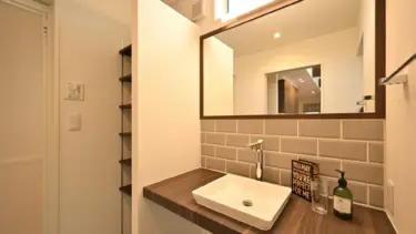 木目のカウンターと、落ち着いたトーンのタイルが美しく調和した洗面スペース