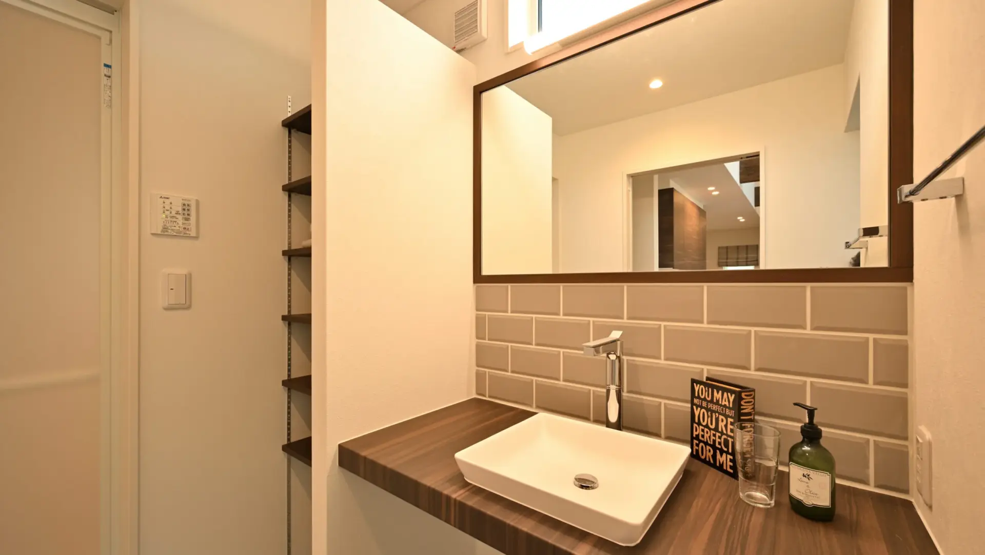 木目のカウンターと、落ち着いたトーンのタイルが美しく調和した洗面スペース