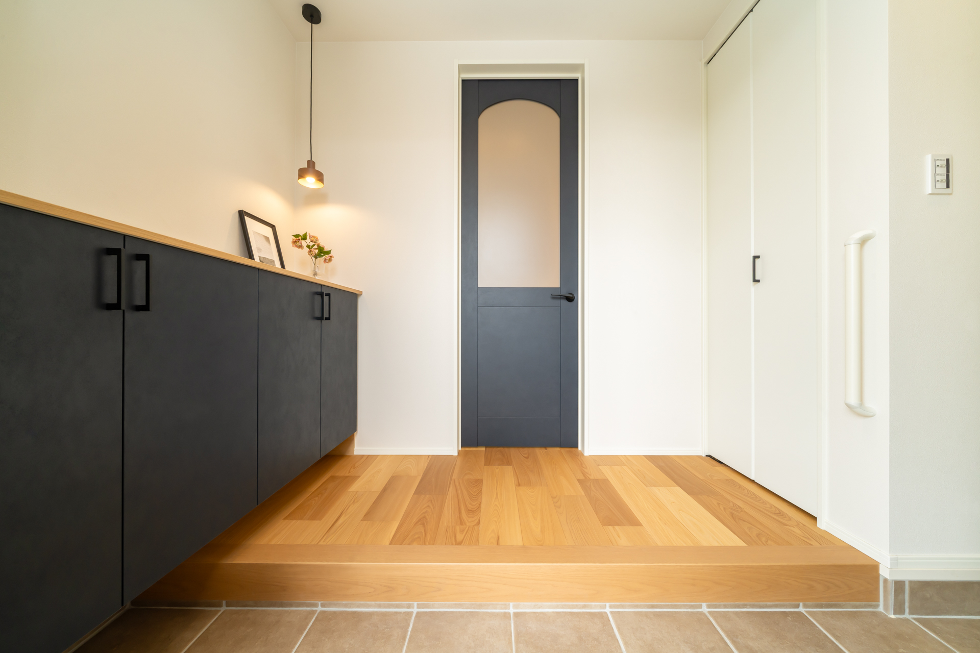 ■玄関（ホール側）
リビングのガラスドアとペンダントライトがおしゃれな玄関。玄関→パントリーへ直接アクセスできるのでお買い物後の片付けがラクラク♪コート掛けや土間収納も備え付けられている。