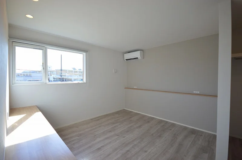 大きな窓から光が差し込む明るい寝室、書斎代わりのテーブルも設けられた多機能空間