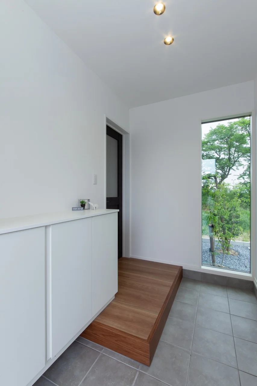 FIX窓の先に植栽の緑が見える玄関