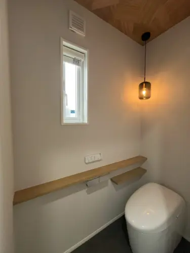 【１階トイレ （タンクレスタイプ）】ペンダントライトと天井の木目がおしゃれなトイレ空間。