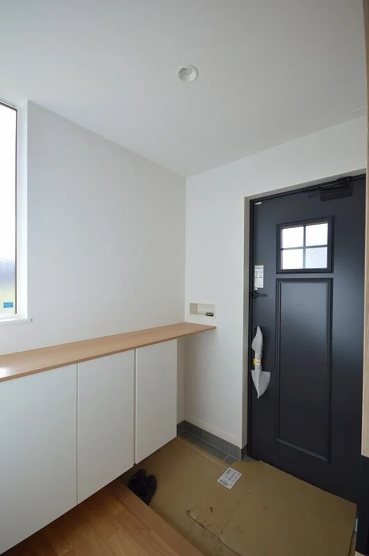 落ち着いた色合いの玄関スペース、収納力のある白いシューズボックス完備