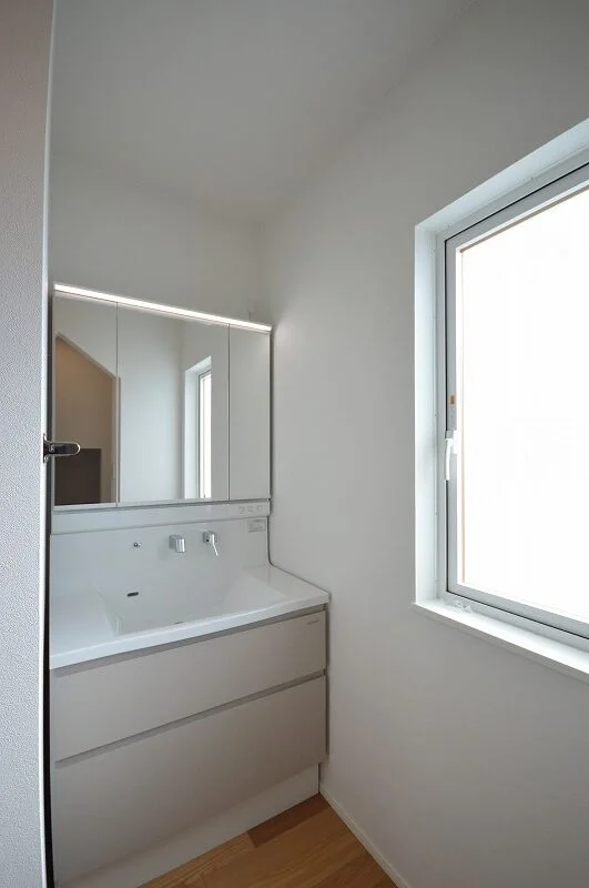 洗面台と大きな三面鏡、清潔感のある白を基調とした水廻り