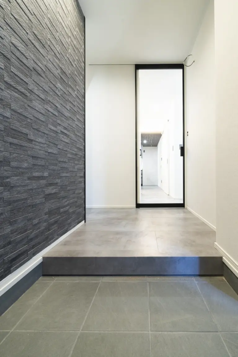 玄関にはタイルの壁面でアクセントを。ガラスドアで開放感も出ます。