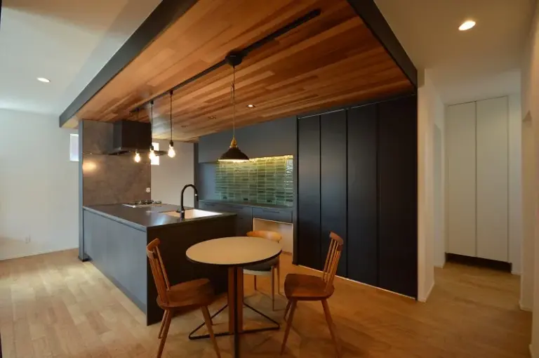 黒と木目が調和するダイニングキッチン、タイルを仄かに照らす間接照明で雰囲気を優雅に