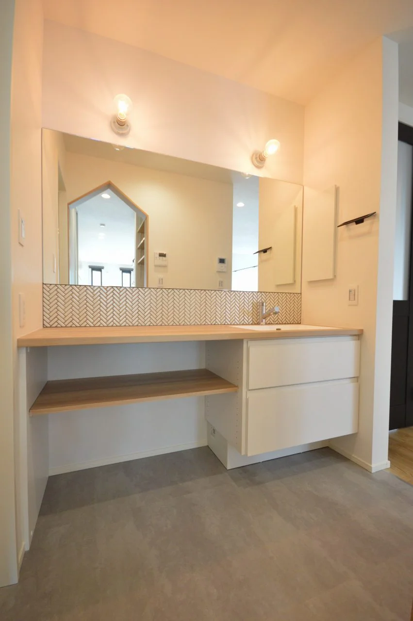 【造作洗面台】 こだわりの照明、単板張りミラー、タイル張り、オーダーのユニット洗面台でオリジナル間のある洗面台。 一間幅に入れた幅広の洗面台で、5人家族でも朝の混み合う時間帯を緩和してくれます。